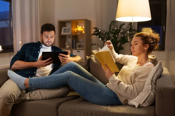 Casal com computador tablet e livro em casa — Fotografia de Stock