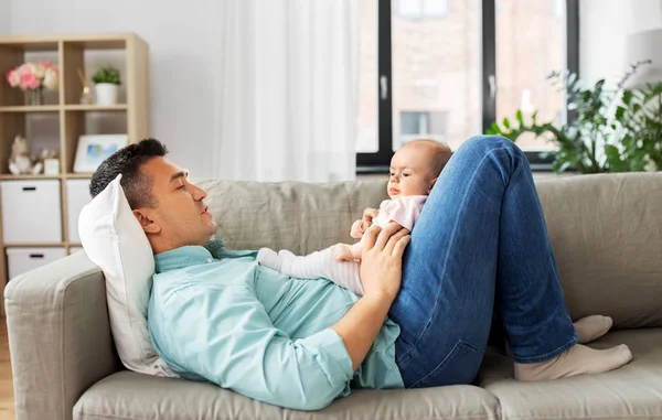 Ayah setengah baya dengan bayi berbaring di sofa di rumah — Stok Foto