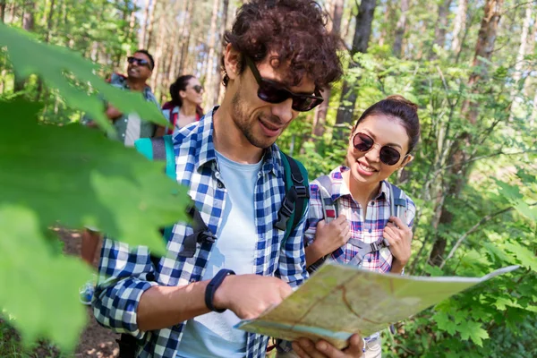 Vrienden met kaart en rugzakken wandelen in het bos — Stockfoto