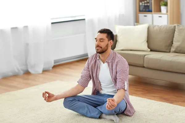 Hombre meditando en la pose de loto en casa —  Fotos de Stock