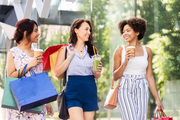 Women with shopping bags and drinks in city — Stock Photo, Image