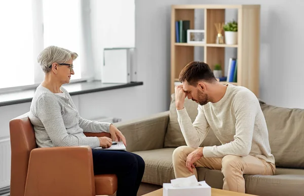 Starší žena psycholog a smutný muž pacient — Stock fotografie