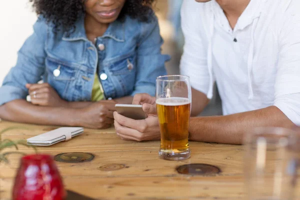 Casal com smartphone e cerveja no bar — Fotografia de Stock