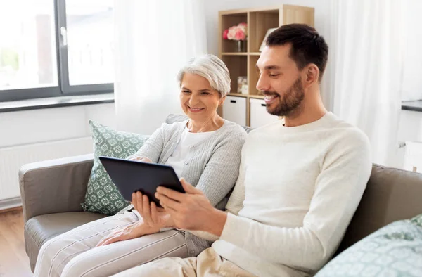 Alte Mutter und erwachsener Sohn mit Tablet-PC zu Hause — Stockfoto