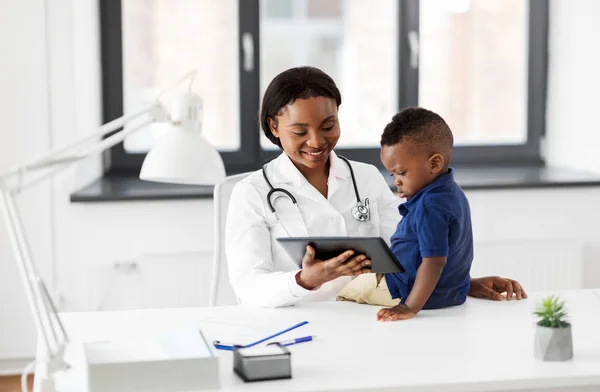 Läkare som visar Tablet PC för baby patient på kliniken — Stockfoto