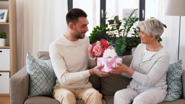 Сын дарит подарок и цветы старшей матери — стоковое видео