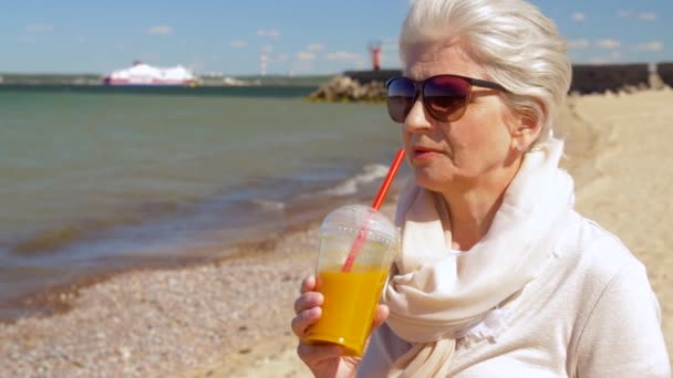 Senior woman drinking shake on summer beach — Stock Video