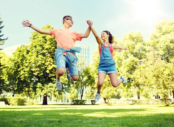 Šťastný dospívající pár jumping v letním parku — Stock fotografie