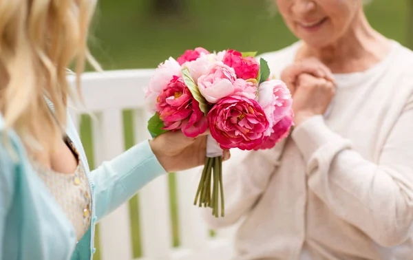 Дочка дає квіти старшій мамі в парку — стокове фото