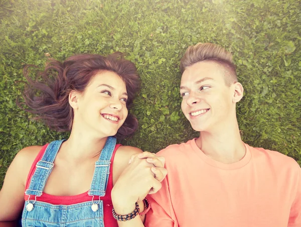 Feliz casal adolescente deitado na grama no verão — Fotografia de Stock