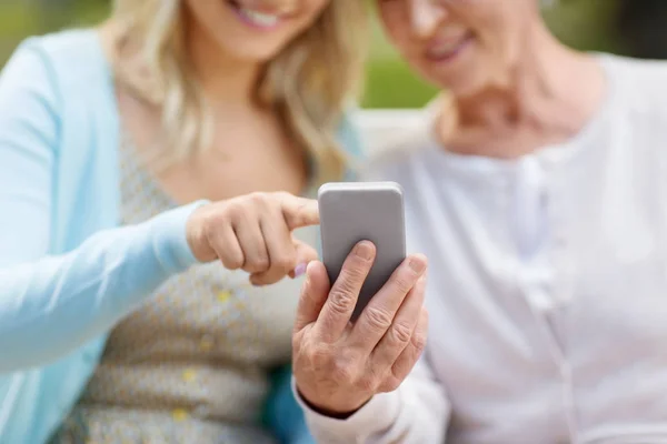 Filha e mãe sênior com smartphone no parque — Fotografia de Stock