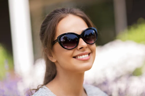 Yaz bahçesinde güneş gözlüklü mutlu bir genç kadın. — Stok fotoğraf