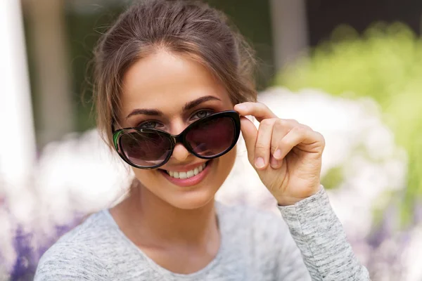 Felice giovane donna in occhiali da sole nel giardino estivo — Foto Stock