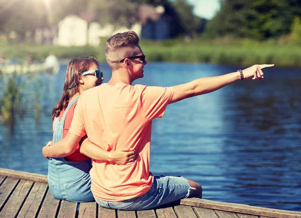 Glückliches Paar zeigt mit dem Finger auf sommerlichen Flussliegeplatz — Stockfoto