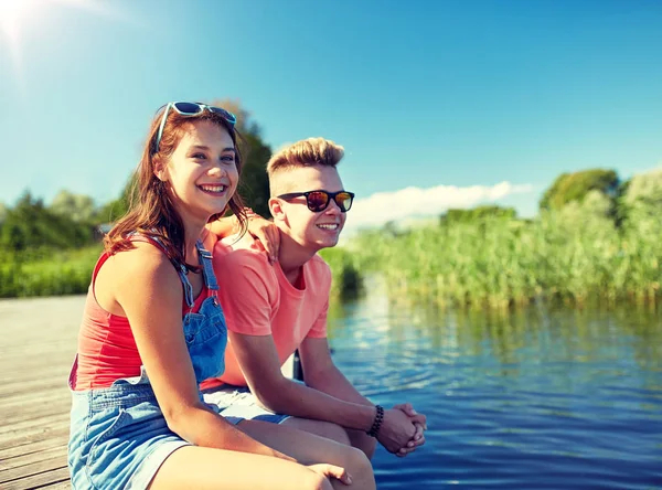 Glückliches Teenie-Paar sitzt auf Flussliegeplatz — Stockfoto