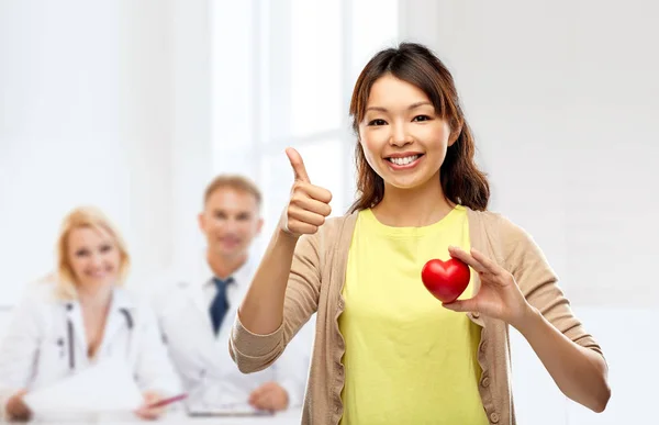 Happy asian woman with red heart showing thumbs up — Stock Photo, Image