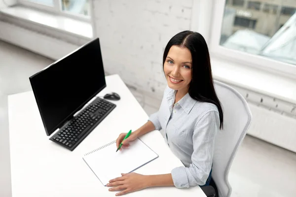 Empresária escrevendo para notebook no escritório — Fotografia de Stock