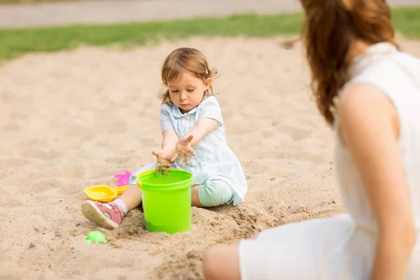 Pequena menina brinca com brinquedos em sandbox — Fotografia de Stock