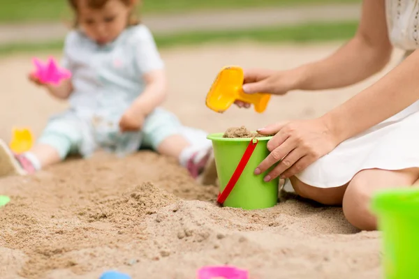 砂場で赤ちゃんの娘と遊ぶ母親 — ストック写真