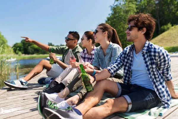 Vrienden drinken bier en cider op de pier van het meer — Stockfoto