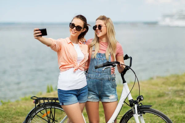 Девушки-подростки на велосипеде делают селфи летом — стоковое фото