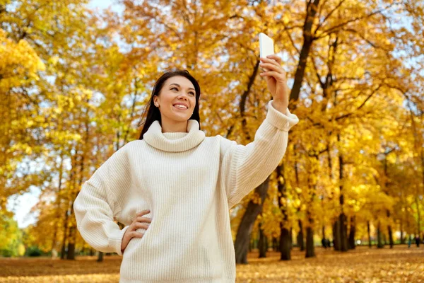 Woman taking selfie by smartphone at autumn park — Stock Photo, Image