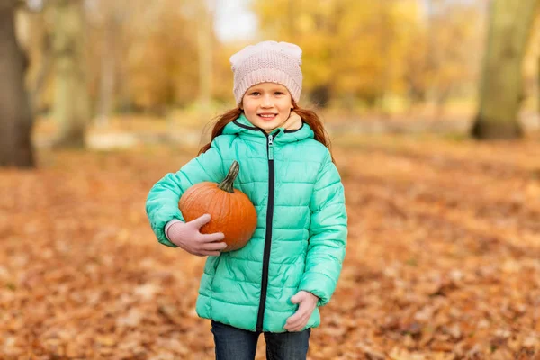 Счастливая маленькая девочка с тыквой в осеннем парке — стоковое фото