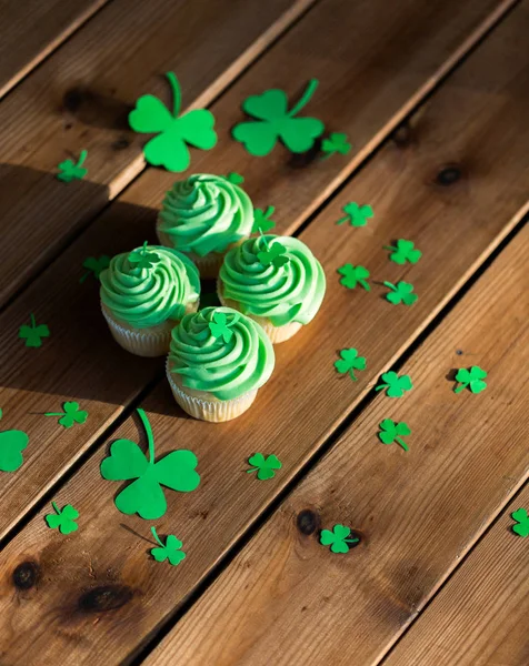 Cupcakes verdes e trevo na mesa de madeira — Fotografia de Stock