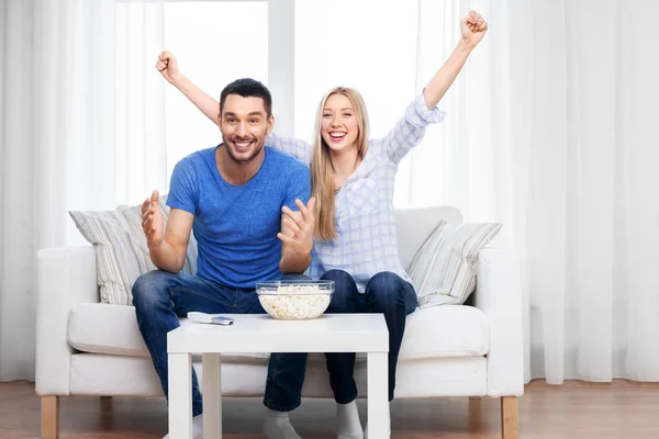 Feliz pareja con palomitas de maíz viendo la televisión en casa — Foto de Stock