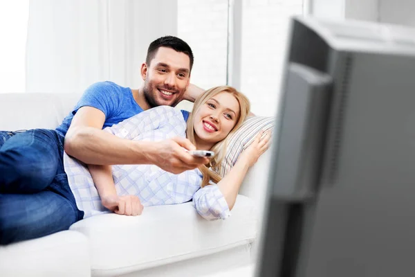 Счастливая улыбающаяся пара смотрит телевизор дома — стоковое фото