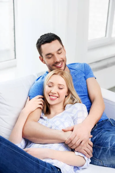 Feliz casal sentado no sofá e abraçando em casa — Fotografia de Stock