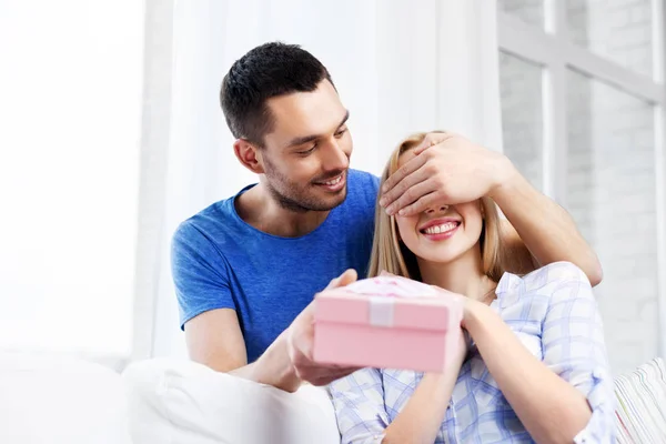 Casal feliz com caixa de presente em casa — Fotografia de Stock