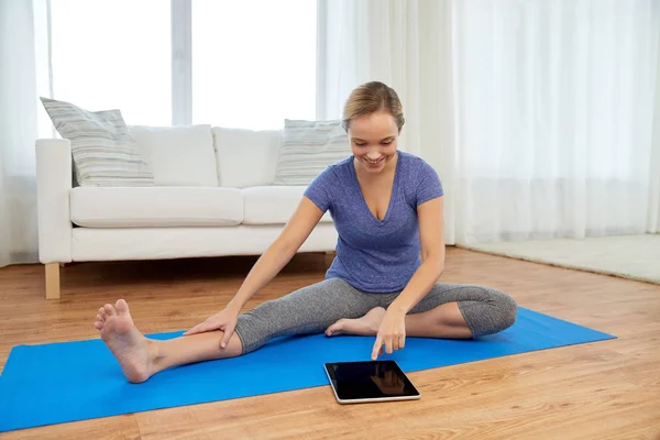 Жінка з планшетним комп'ютером робить йогу вдома — стокове фото