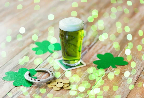 Glas groene bier, hoefijzer en gouden munten — Stockfoto