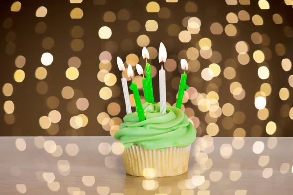 Зеленый кекс с шестью горящими свечами на столе — стоковое фото