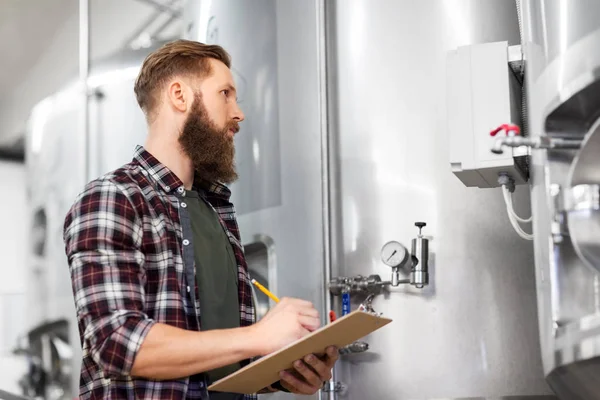 Hombre con portapapeles en cervecería artesanal o fábrica de cerveza —  Fotos de Stock