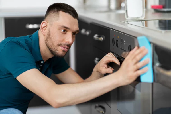 Man met doek schoonmaken van de oven deur huis keuken — Stockfoto