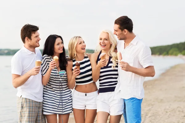 Happy friends eating ice cream on beach — Stock Photo, Image