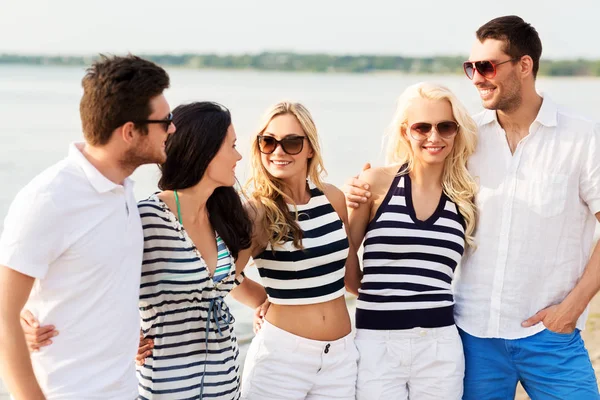 Grupp glada vänner i randiga kläder på stranden — Stockfoto