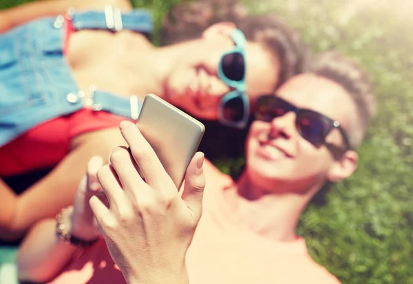 Счастливая пара подростков смартфон лежал на траве — стоковое фото