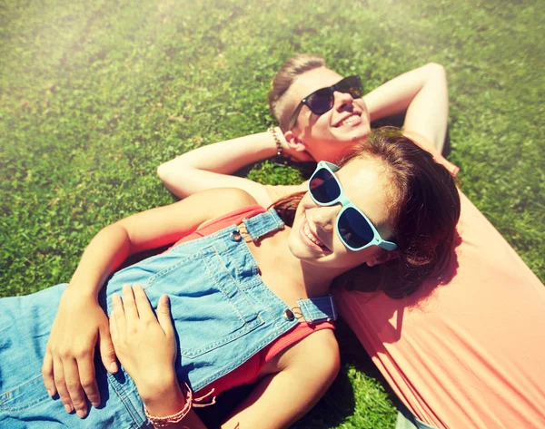 Feliz casal adolescente deitado na grama no verão — Fotografia de Stock