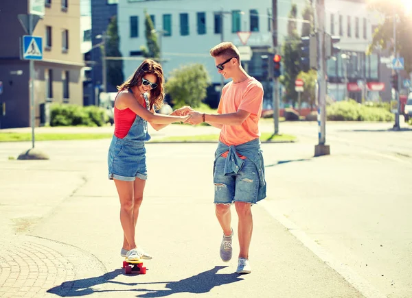 Teenage couple riding skateboards on city street — Stock Photo, Image