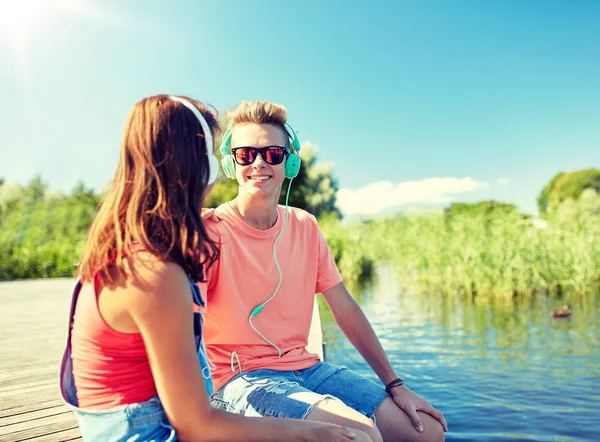 Gelukkige tiener paar met koptelefoon op rivier ligplaats — Stockfoto