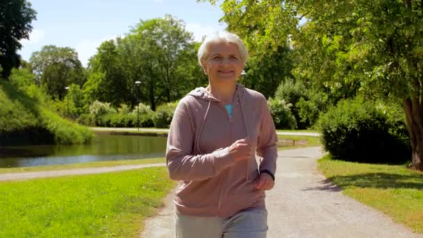 Старшая женщина бегает по летнему парку — стоковое видео