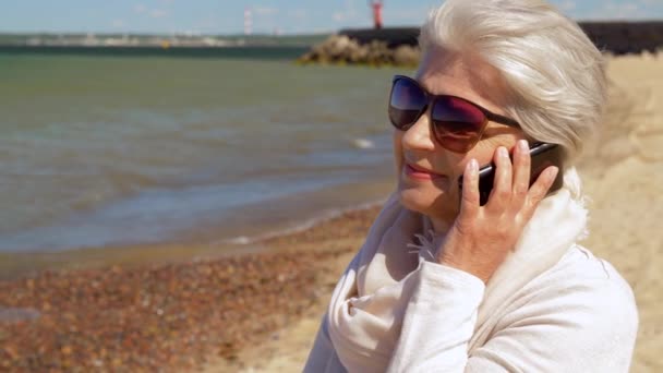 여름 해변에서 스마트 폰을 호출하는 수석 여성 — 비디오