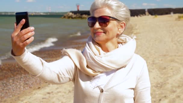 Senior woman taking selfie by smartphone on beach — Stock Video