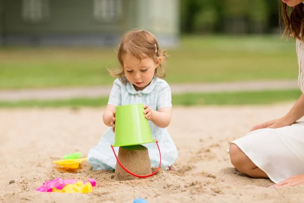 小さな女の子はサンドボックスでおもちゃで遊ぶ — ストック写真