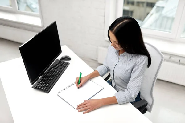 Businesswoman writing to notebook at office — Stock Photo, Image