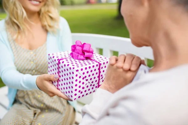Hija dando regalo a la madre mayor en el parque —  Fotos de Stock