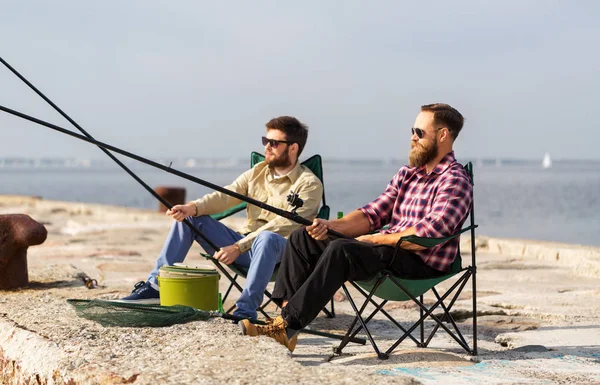 Amigos masculinos com varas de pesca no cais do mar — Fotografia de Stock